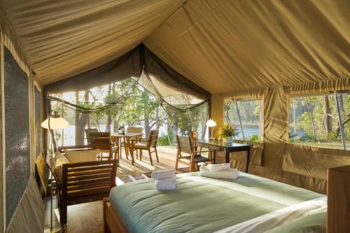 a tent bedroom with a bed and a table and chairs at Tanja Lagoon Camp in Tanja