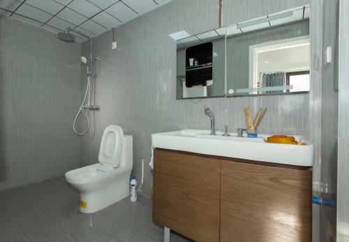 a bathroom with a sink and a toilet and a mirror at Sunny Apartment, minutes to beach in Shuijiao