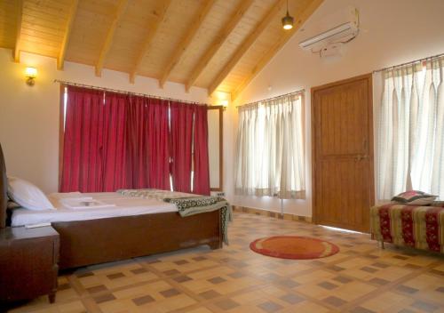 um quarto com uma cama grande e cortinas vermelhas em Camp Banas Naudhiya em Budia