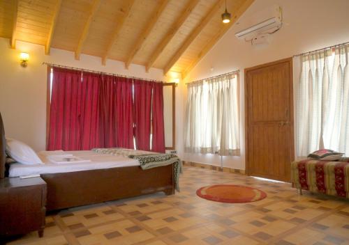 a bedroom with a large bed and red curtains at Camp Banas Naudhiya in Budia