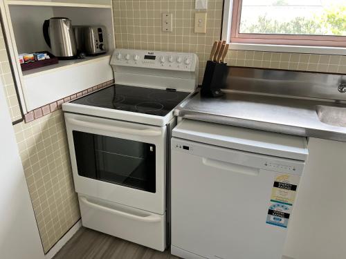 a kitchen with a stove top oven next to a sink at Parkview Holiday Homes "Opposite of Famous Kuirau Park" in Rotorua