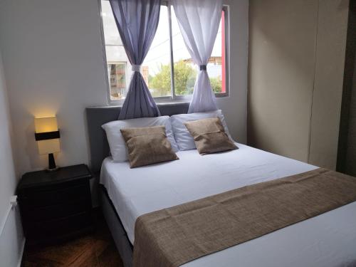 a bedroom with a white bed with a window at APARTAMENTO BALCON DE LA ESPERANZA GUATAPE in Guatapé