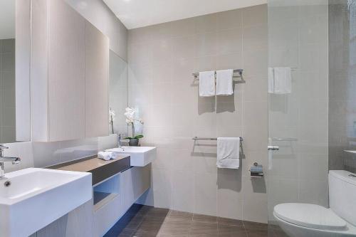 a white bathroom with a sink and a toilet at Top of Taringa Penthouse with Sweeping Views in Brisbane