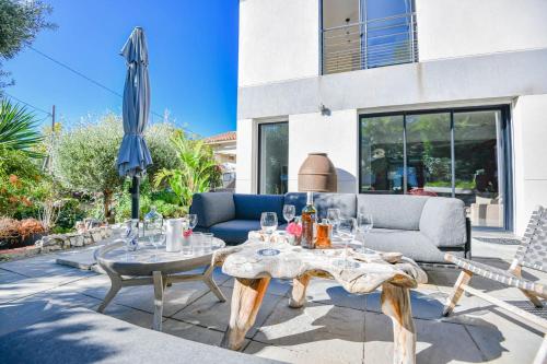 a patio with a couch and tables and an umbrella at Villa Notre-Dame - Piscine parking 4 chambres in Marseille