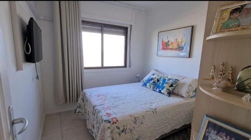 a small bedroom with a bed and a window at Apartamento Beira mar Capão da Canoa in Capão da Canoa