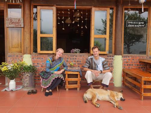 a man and a woman sitting in front of a building with a dog at La Beauté Sa Pa in Sa Pa