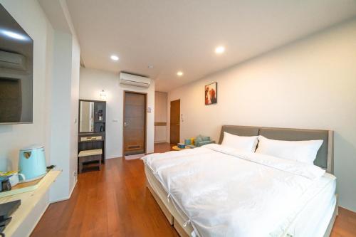 a bedroom with a large white bed and a television at Luodong warm house in Luodong