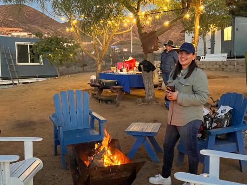 a woman standing next to a fire and chairs at Ecovino Valle de Guadalupe in Valle de Guadalupe