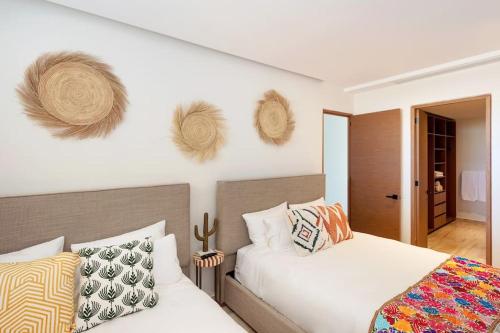 a bedroom with two beds and hats on the wall at Luxurious Ocean View Apartment in Cabo San Lucas