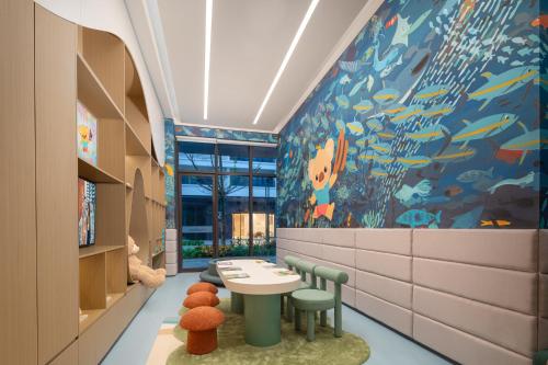 a room with a table and chairs and a fish mural at Citadines Hope City Boao in Qionghai