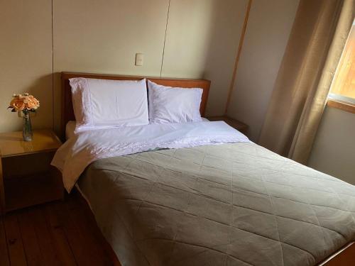 uma cama com lençóis brancos e almofadas num quarto em Cabaña Paso De Los Toros, San Fabian de Alico em San Fabián de Alico