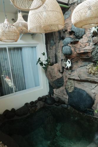 a rock wall with a pool of water next to a window at Casa Bonita: Stylish, Affordable Home & Mini Pool in Kalasan