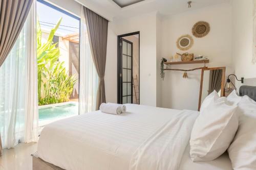a bedroom with a white bed and a large window at Kamaratih Villas by Maheswara in Legian