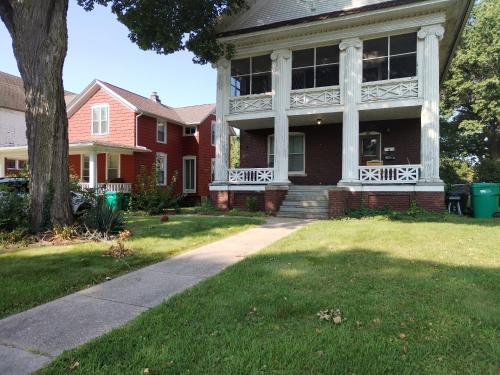 a red house with white pillars on the front of it at Cool and affordable apartment Galesburg in Galesburg