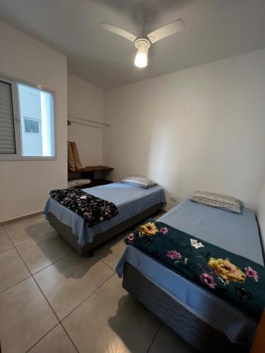 um quarto com 2 camas e uma ventoinha de tecto em Apê212 - 650m da Orla em Ubatuba