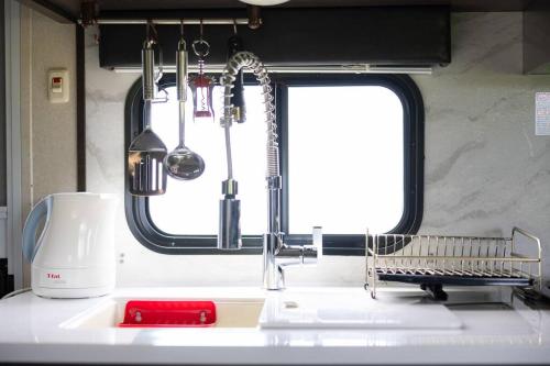 a kitchen counter with a sink with a mixer and a window at Natural farm Zanpa -SEVEN Hotels and Resorts- in Yomitan