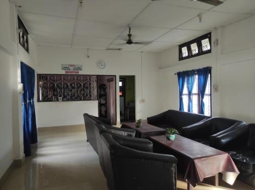 a waiting room with couches and a table and chairs at Duda Lodge in Tezu