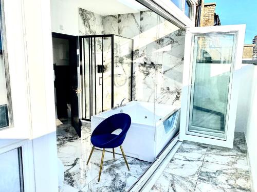 baño con silla azul y lavamanos en Duke and Duchess Apartments and Rooms - Private in Room Hot Tub Suites en Londres