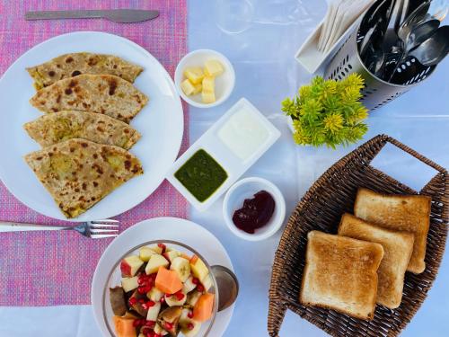 einen Tisch mit einem Teller Essen mit Toast und einer Schüssel Salat in der Unterkunft The Castle View Homestay in Bundi