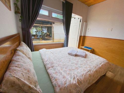 a bedroom with a large bed with a window at Oak Village by D Home Da Lat in Da Lat
