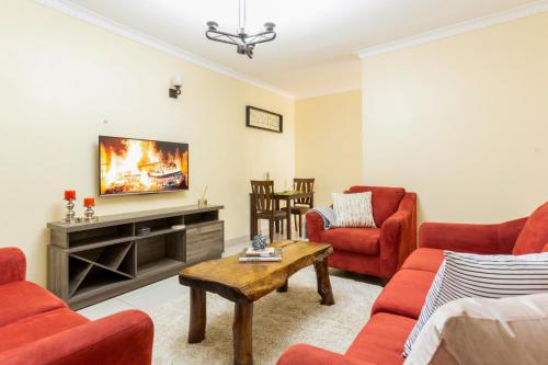 a living room with red chairs and a flat screen tv at Neema Suites, Ngong RD near Junction in Nairobi