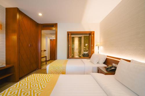 a hotel room with two beds and a window at The Royal Paradise Hotel & Spa - SHA Extra Plus in Patong Beach