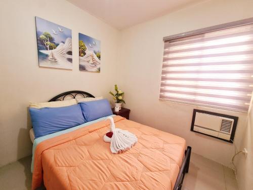 sypialnia z pomarańczowym łóżkiem i wypchanym zwierzakiem w obiekcie Fully Furnished Apartment with Netflix and Wifi w mieście Batangas