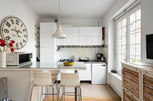 une cuisine avec des armoires blanches et une table et des chaises dans l'établissement Appartement Au Coeur D'intra Muros, à Saint-Malo