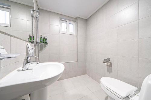 a white bathroom with a sink and a toilet at HOTEL mini in Busan