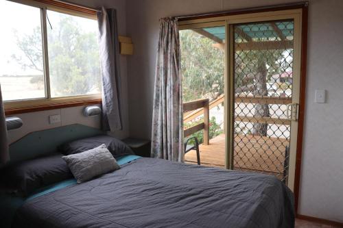 a bedroom with a bed and a window and a balcony at Coodlie Park Eco Retreat in Talia