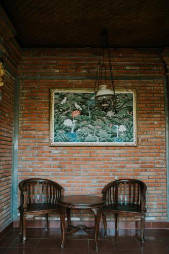 a table and two chairs next to a brick wall at Jati 3 Bungalows in Ubud