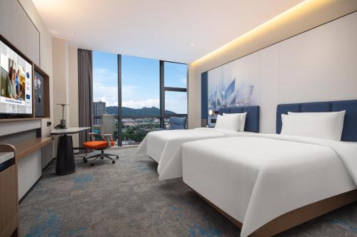 una camera d'albergo con due letti e una televisione di Hilton by Hampton Guangzhou Xintang a Zengcheng