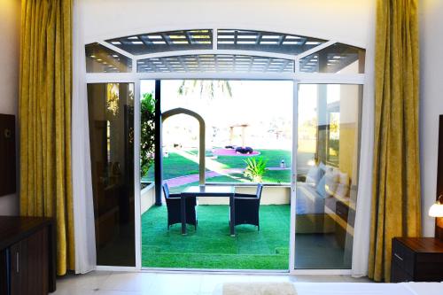 een kamer met een tafel en uitzicht op een tuin bij Samharam Resort Salalah in Salalah