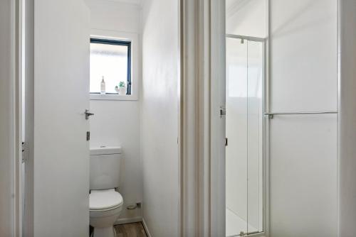 a bathroom with a toilet and a glass shower at Ultimate beach location in Mount Maunganui