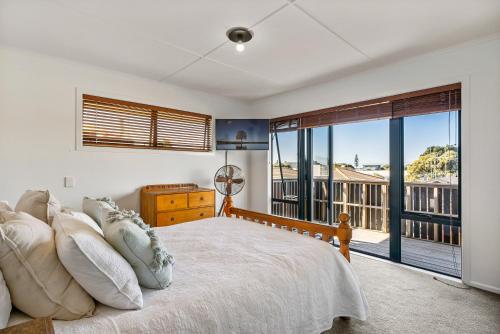 een slaapkamer met een bed en een groot raam bij Ultimate beach location in Mount Maunganui