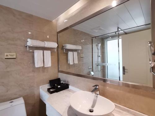 ein Bad mit einem Waschbecken und einem Spiegel in der Unterkunft 慧兰酒店bodhi hotel 