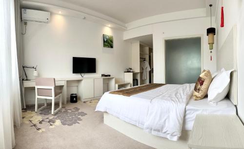 1 dormitorio con 1 cama y escritorio con TV en 慧兰酒店bodhi hotel, 