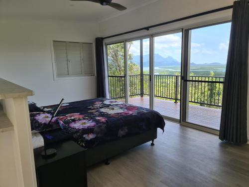 a bedroom with a bed and a large sliding glass door at Vista Hinchinbrook in Cardwell