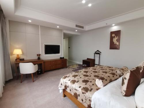 a bedroom with two beds and a desk and a television at 慧兰酒店bodhi hotel in Ban Botèn