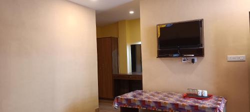a room with a tv on the wall and a table at Joye Grand Hotel in Havelock Island