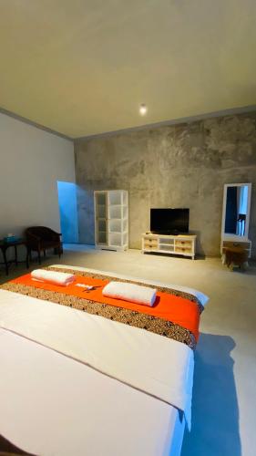 a bedroom with a large bed and a flat screen tv at Omah Najwa by Sampai Coliving in Kejayan