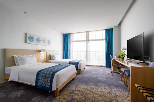 una camera d'albergo con due letti e una televisione di 石家庄诺华廷酒店 Novlion hotel a Shijiazhuang