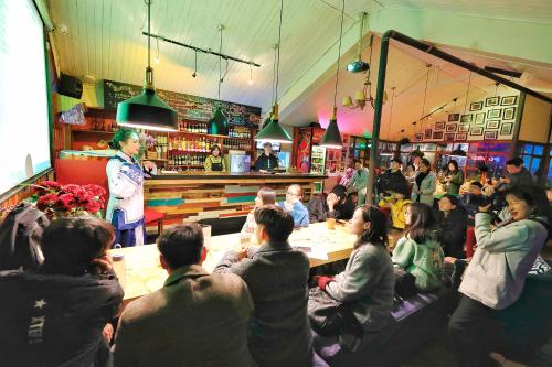 a crowd of people sitting in a restaurant with a chef at Kunming Upland International Youth Hostel ,near the city center ,2 mins walk to the subway, 2 mins walk to the Green Lake, Close to Yuan tong Temple, Old street, Yunnan University, convenient payment and visa cards are accepted in Kunming