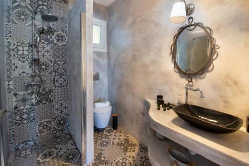 uma casa de banho com um lavatório, um espelho e um chuveiro em Vasia's Artistsvillas em Gaios