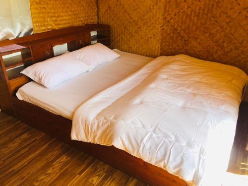 uma cama com lençóis brancos e almofadas num quarto em Pai Kitchen Hub Hostel em Pai