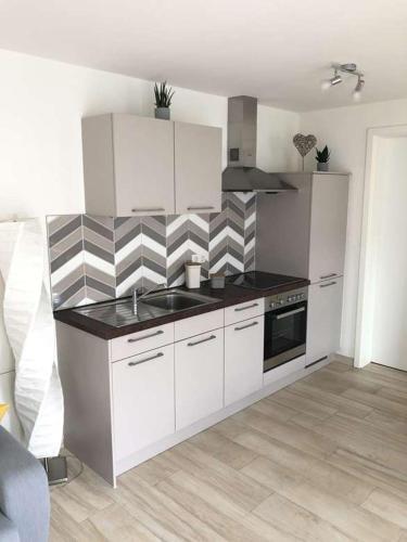 a kitchen with white cabinets and a black counter top at 2 Zimmer Traum mit Terrasse am Kocher Jagst Radweg nähe Heilbronn in Bad Friedrichshall