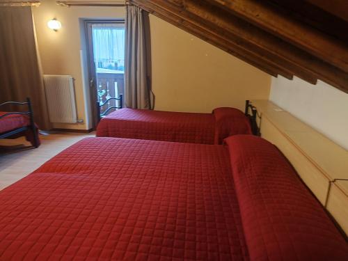 two red beds in a room with a window at Garnì Bonsai in Pinzolo