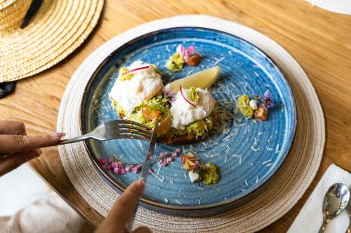 a person eating food on a blue plate with a fork at Proud Phu Fah Muang Chiang Mai in Chiang Mai