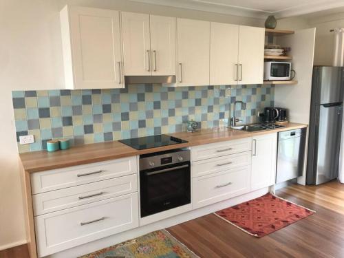 a kitchen with white cabinets and a stove top oven at Shelly Beach Townhouse in East Ballina