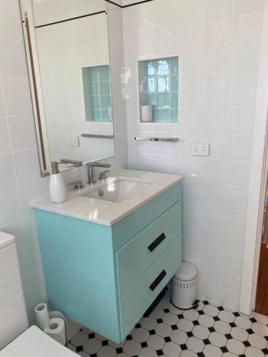 a bathroom with a blue sink and a mirror at Shelly Beach Townhouse in East Ballina